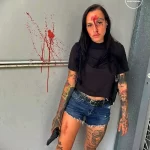 Фото тату: девушка с множеством татуировок на теле, держащая пистолет, демонстрирует дерзкий и провокационный образ.