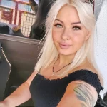 Фотография девушки с татуировкой на руке и плече. Татуировка имеет сложный рисунок с использованием различных цветов и оттенков.
