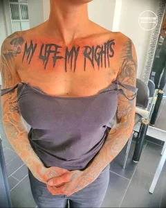 Фотография женщины с татуировкой надписи 'MY LIFE MY RIGHTS' на груди. Татуировка выполнена в простом, но выразительном стиле.