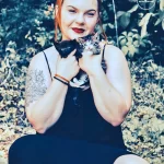 Фотография девушки, держащей котят, с видимой татуировкой на предплечье. Изображение демонстрирует сочетание нежности и художественного самовыражения.