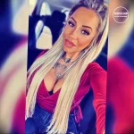 Фотография девушки с татуировкой на груди, изображающей бабочку и цветы, выполненной в ярких цветах.