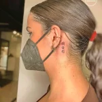 Фото татуировки с иероглифами на шее девушки в медицинской маске. Тонкие линии и минималистичный дизайн.