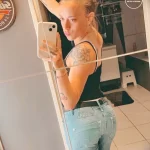 Фотография девушки с нежными татуировками в виде цветов и узоров на руке и боку, демонстрирующая женственность и изящество.