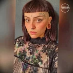 Фото тату на лице и шее: портрет девушки с необычным макияжем и цветочными элементами, выполненный в ярких цветах и графическом стиле.