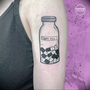 Фото тату на руке: минималистичное изображение баночки с надписью 'Happy Pills' и таблетками внутри, выполненное в черном цвете.