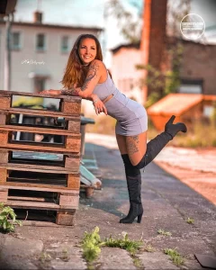 Фотография девушки в шортах и майке, демонстрирующей татуировки на ноге и плече.