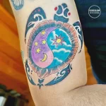 Фото тату: красочная татуировка черепахи с изображением солнца, луны и звезд на панцире, выполненная в стиле олд скул.