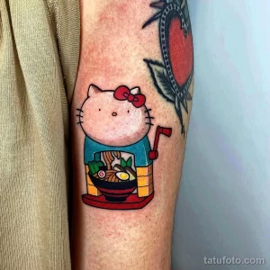 Фото яркой татуировки Hello Kitty, наслаждающейся блюдом рамэн. Забавный и красочный рисунок.