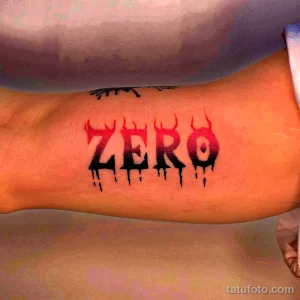 Фото тату с надписью 'ZERO', выполненной в красном цвете с эффектом стекающих капель. Рисунок расположен на предплечье.