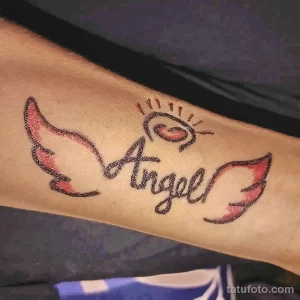 Фото татуировки: надпись "Angel" с изображением крыльев, выполненная на руке. Нежный и минималистичный рисунок.