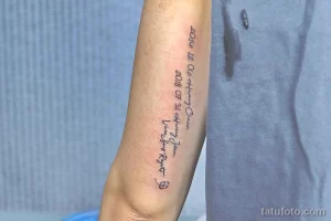 Фото минималистичной татуировки с надписью дат и имени, выполненной тонкой линией на руке.