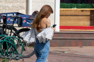 Крупный план татуировки на спине девушки, изображающей абстрактный узор. Минималистичный стиль и черные линии.