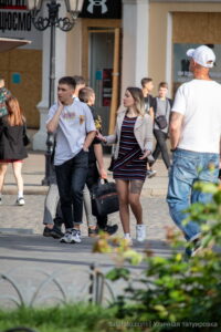 Фото тату: девушка в пиджаке и юбке, с татуировкой с портретом Джонни Деппа на бедре, прогуливается по городу.