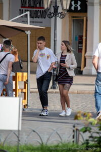 Фото тату: девушка в пиджаке и юбке, с татуировкой с портретом Джонни Деппа на бедре, разговаривает по телефону.