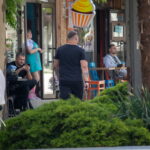 Фото тату на плече мужчины: небольшой рисунок, предположительно, в стиле минимализм или геометрия. Видна часть татуировки на плече, когда мужчина стоит спиной.
