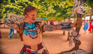 Фото тату рукава с изображением воина из игры Horizon Zero Dawn, держащего лук. Детализированный рисунок татуировки в ярких цветах.