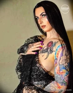 Фото тату на груди девушки, выполненное в ярких цветах. Изображена стрела, пронзающая цветы, и другие декоративные элементы.