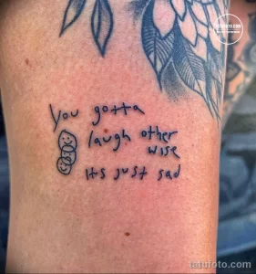 Фото тату на руке с надписью "You gotta laugh otherwise it's just sad" и небольшим рисунком смайлика. Рисунок выполнен в красном цвете.
