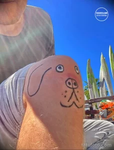 Фото тату с изображением милой мордочки щенка, выполненной в стиле олдскул на плече. Яркий рисунок татуировки с четкими контурами.