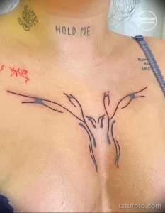 Минималистичное тату на груди с надписью 'Hold Me' и изображением птицы. Черно-белый рисунок, тонкие линии, эмоциональный сюжет.