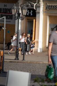 Фотография уличной татуировки на ноге женщины, идущей по городу. Видны детали рисунка и его расположение на теле.
