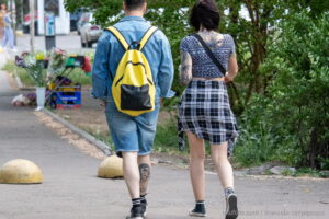 Фотография пары, идущей по улице. У мужчины и женщины видны татуировки на руках и ногах. На ноге мужчины изображен череп.