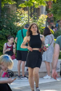 Фото тату на плече девушки, выполненное в черном цвете. Рисунок представляет собой абстрактный узор, напоминающий ветви дерева или морские волны. Девушка держит в руке бутылку напитка.