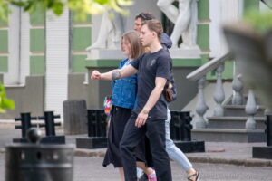 Фото мужчины с татуировкой на руке, идущего по улице с девушкой. Черно-серые татуировки, реалистичный рисунок татуировки, мастер тату.