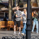 Фотография мужчины с татуировками на ногах, идущего по улице. Видны татуировки в виде надписей и изображения головы тигра.
