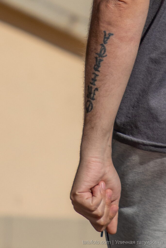 мужчина с низкой качественной татуировкой надписью на запястье левой руки44 - Уличная тату 22062022 №401 - tatufoto.com