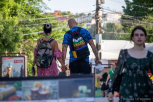 Фото татуировок на руках и спине мужчины, выполненных в черном цвете. Изображены иероглифы и абстрактные узоры. Снимок сделан на улице, в движении.