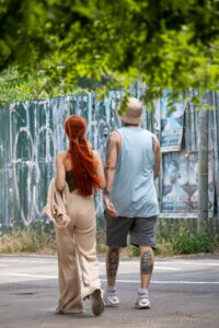Фото тату на теле мужчины и женщины, идущих по улице. Вид сзади, акцент на татуировках на руках и ногах.