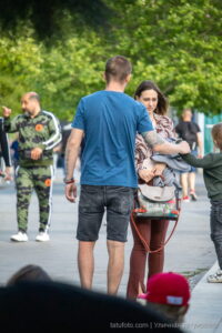 Фото мужчины с татуировкой на руке, держащего за руку ребенка. Татуировка выполнена в темных тонах и состоит из геометрических узоров и надписей.