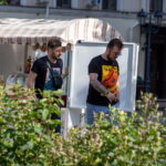 Фотография двух мужчин, один из которых имеет татуировку на руке, идущих по улице. Татуировка выполнена в черно-серых тонах.