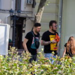 Фотография двух мужчин, один из которых имеет татуировку на руке, идущих по улице. Татуировка выполнена в черно-серых тонах.