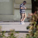 Фотография мужчины с татуировками на руках и плечах, использующего смартфон. Современный городской стиль.