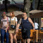 Фото тату на плече мужчины: темный рисунок, возможно, в виде узора или символа. Видна татуировка на плече, когда мужчина идет с женщиной.