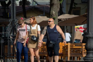 Фото тату на плече мужчины: темный рисунок, возможно, в виде узора или символа. Видна татуировка на плече, когда мужчина идет с женщиной.