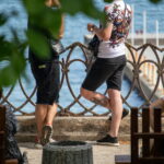 Фото тату на спине мужчины: красочный рисунок в японском стиле с изображением карпа кои, цветов и волн. Детализированная проработка и яркие цвета.
