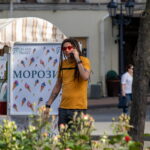Фото мужчины с дредами, говорящего по телефону. На руках и шее видны татуировки в темных тонах. Рисунок татуировки выполнен в стиле графика.