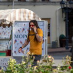 Фото мужчины с дредами, говорящего по телефону. На руках и шее видны татуировки в темных тонах. Рисунок татуировки выполнен в стиле графика.
