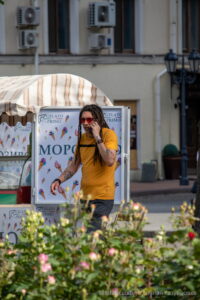 Фото мужчины с дредами, говорящего по телефону. На руках и шее видны татуировки в темных тонах. Рисунок татуировки выполнен в стиле графика.