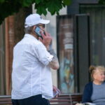 Фото тату на руке мужчины, говорящего по телефону. Видны детализированные рисунки татуировки в стиле олдскул на предплечье.