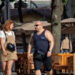 Фото мужчины с татуировкой на плече, стоящего рядом с двумя женщинами. На плече мужчины видна татуировка с изображением дракона.