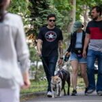 Фото мужчины с татуировкой на руке, выгуливающего двух собак. На руке мужчины видна татуировка с черепом и цветами.