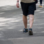 Фотография татуировки на ноге, изображающей яблоко с силуэтом дракона внутри. Снято сбоку, акцент на детали рисунка.