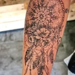 Фото тату ловца снов в стиле blackwork на руке. Изображение выполнено полностью в черном цвете с использованием сложных узоров и геометрических фигур.