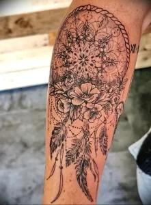 Фото тату ловца снов в стиле blackwork на руке. Изображение выполнено полностью в черном цвете с использованием сложных узоров и геометрических фигур.