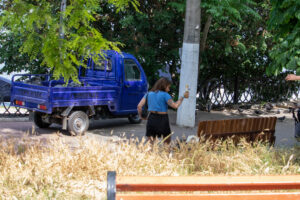 Фото тату на руке девушки, изображающее яркий рисунок с цветами и другими элементами, выполненный в красочном стиле. Татуировка частично видна на фоне городского пейзажа.