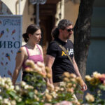 Фотография мужчины и женщины, идущих по улице. У женщины видна татуировка на плече, у мужчины - на предплечье. Яркий солнечный день.